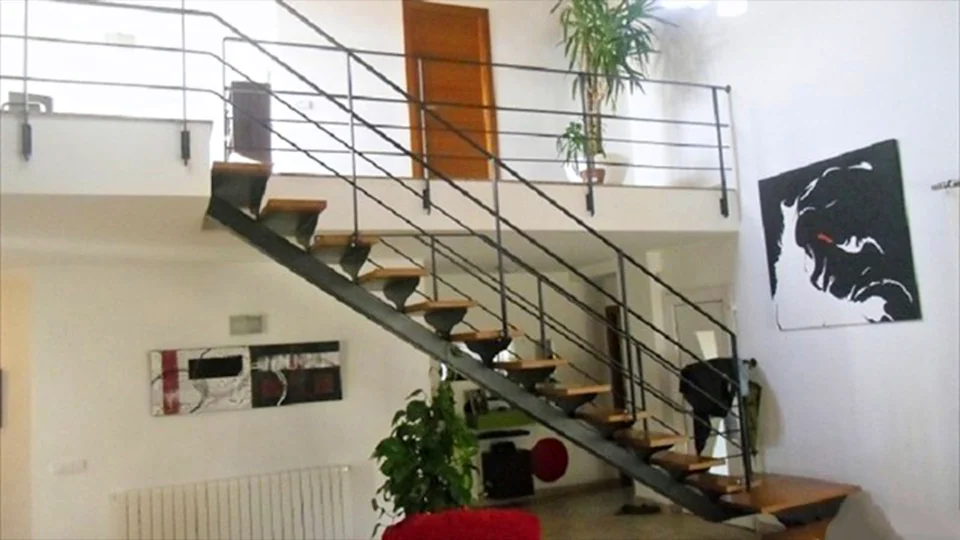 Escalera de estructura metálica con peldaños de madera y barandilla de hierro