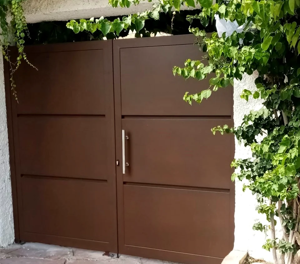 Puerta metálica marrón de dos hojas instalada por CELAE en una vivienda