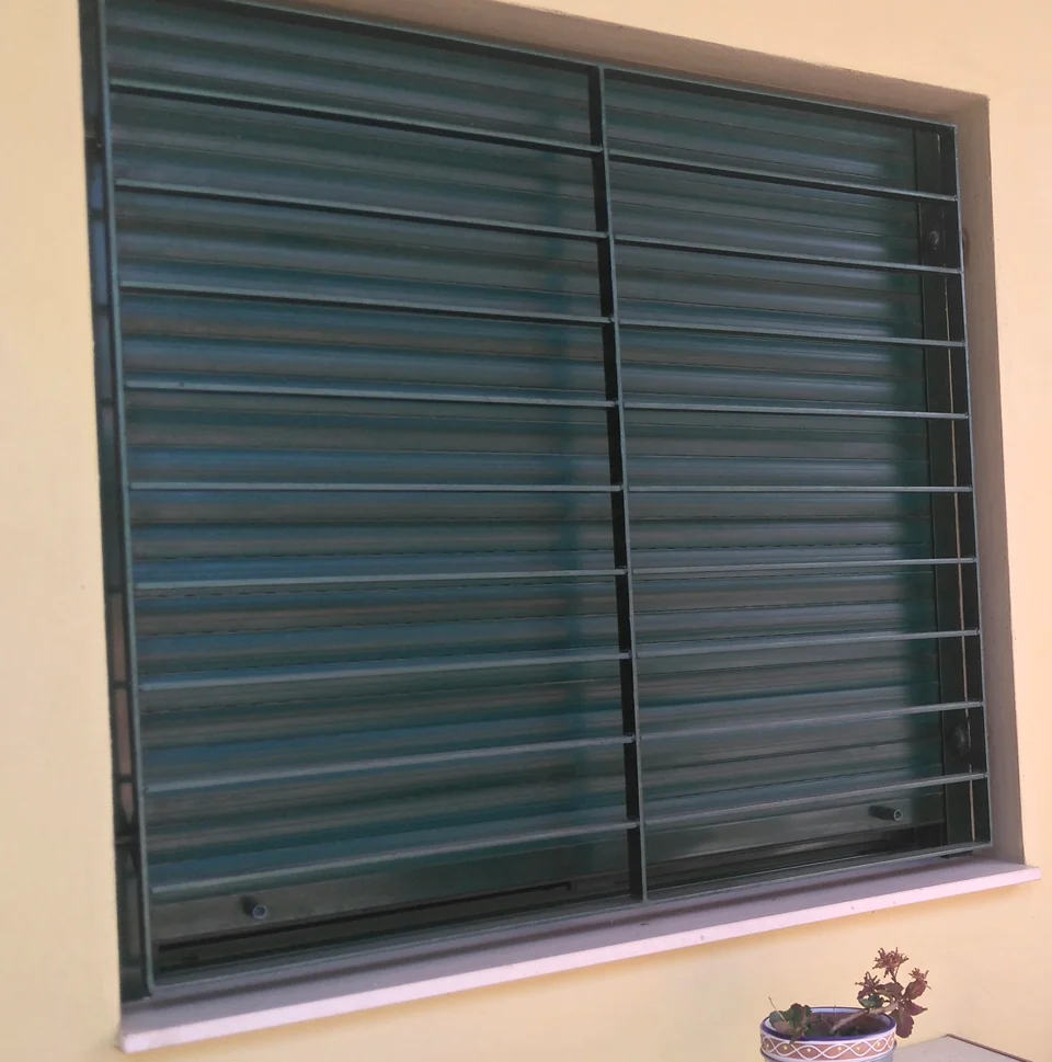 Reja oscura de barras horizontales instalada sobre una ventana